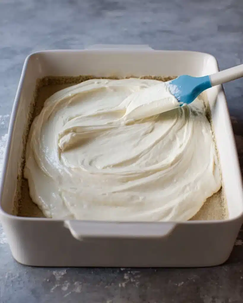Cheesecake filling spread over crust for Apple Cheesecake Bars