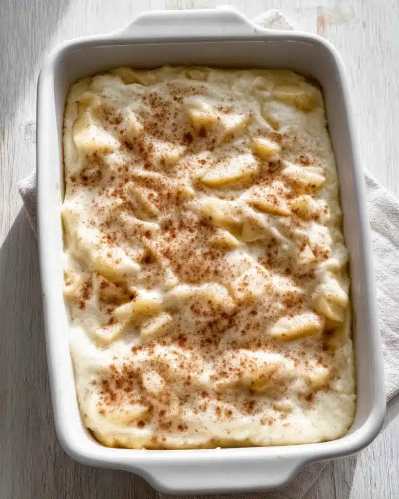 Easy Apple Cobbler Recipe (Perfect for Thanksgiving) 3 Apple cobbler batter spread over apples in baking dish with cinnamon