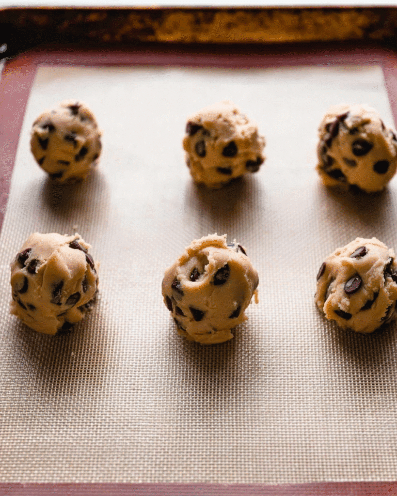 Tall chocolate chip cookie dough balls on baking sheet before baking