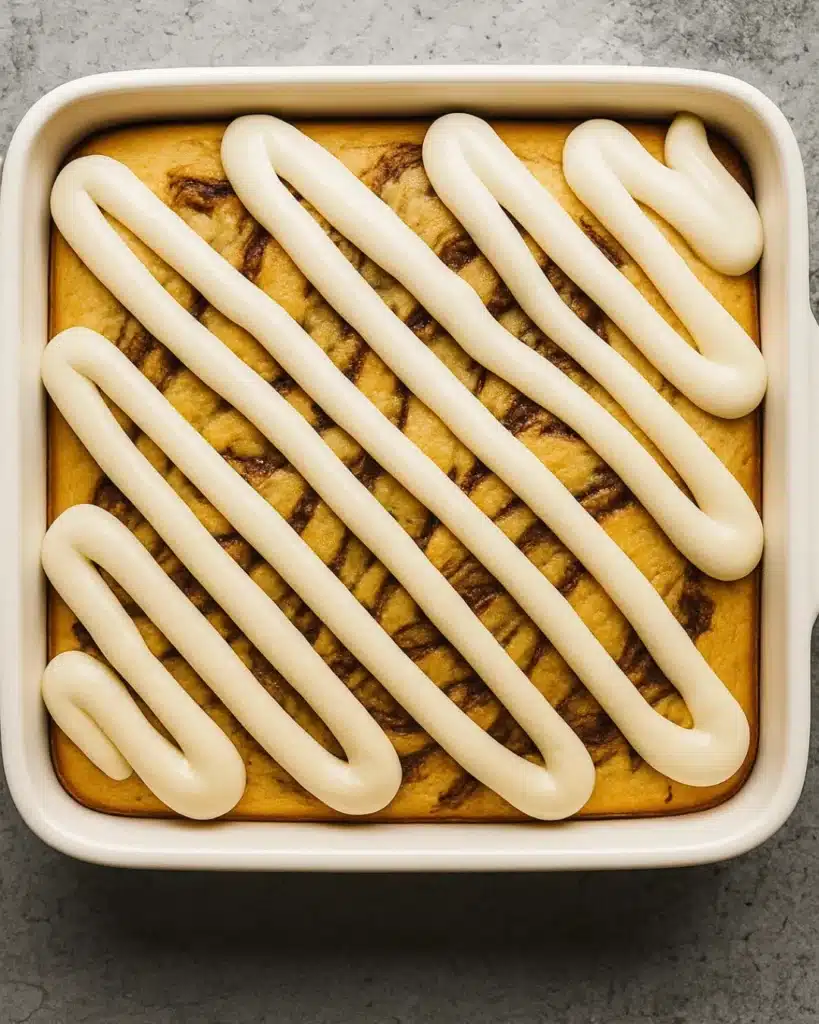 Baked Cinnamon Roll Cake with Cream Cheese Frosting piped on top