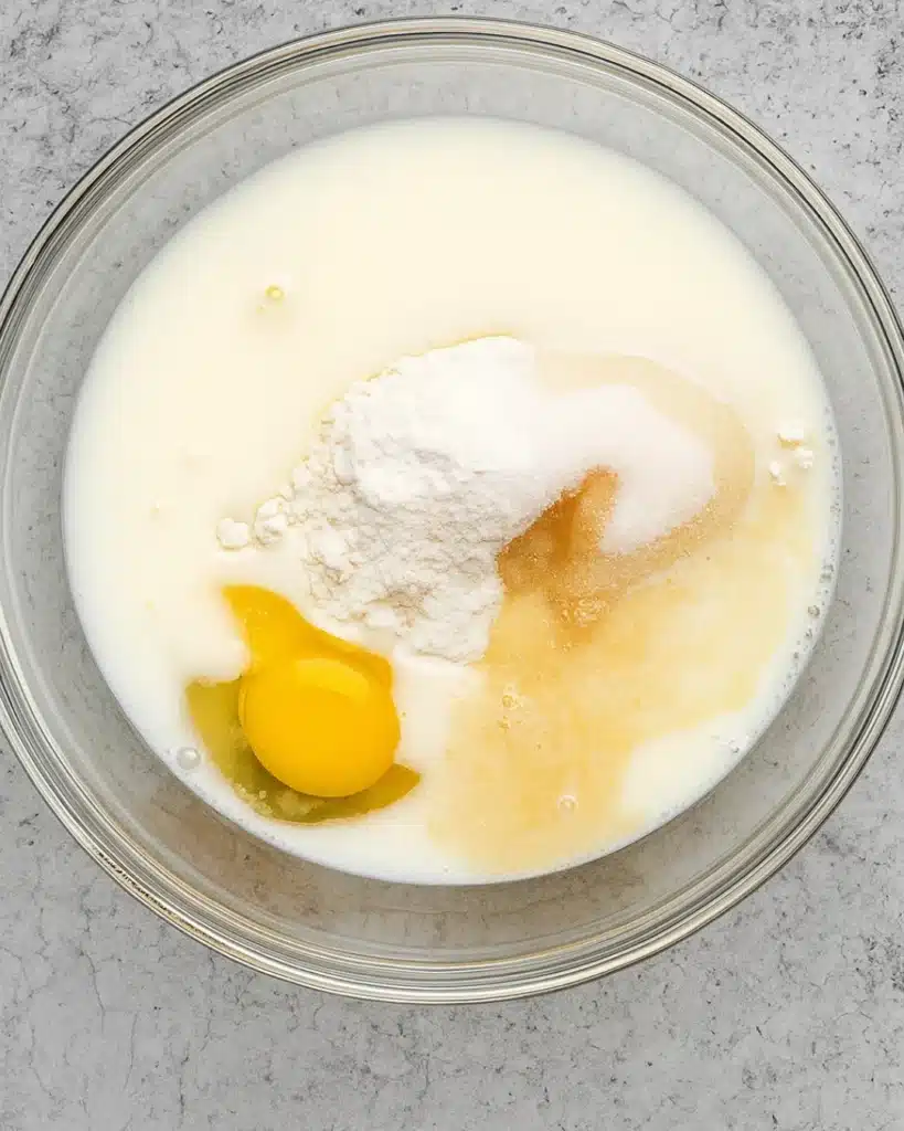 Cinnamon Roll Cake with Cream Cheese Frosting batter ingredients in a glass bowl