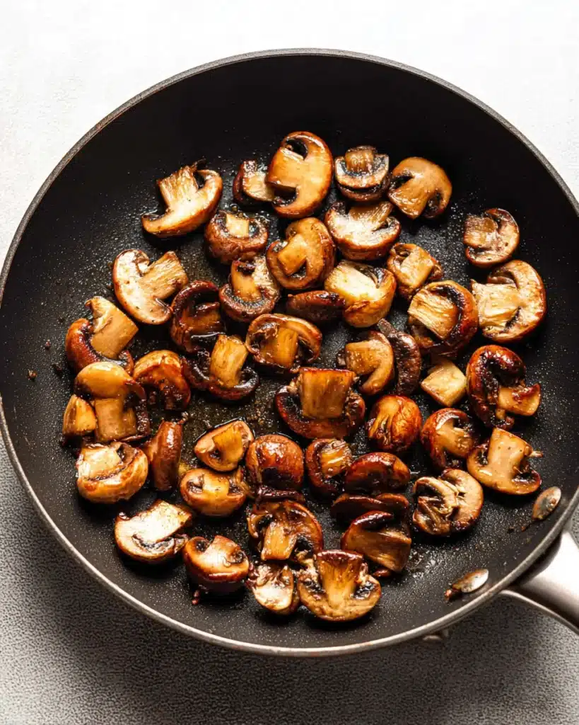 Golden-brown mushrooms searing in skillet for classic beef bourguignon