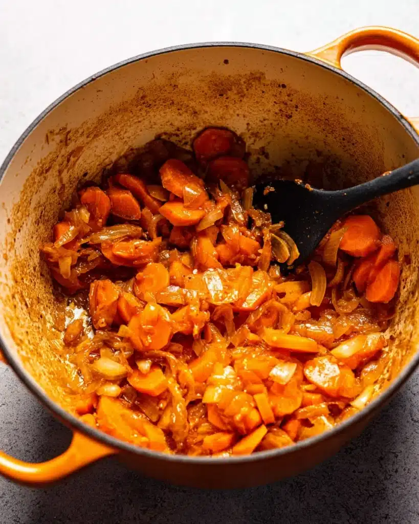 Carrots and onions sautéing in Dutch oven for classic beef bourguignon