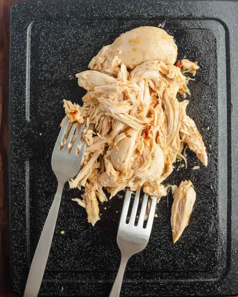 CrockPot Cheesy Chicken Spaghetti Recipe 3 Shredding cooked chicken with forks for CrockPot Cheesy Chicken Spaghetti