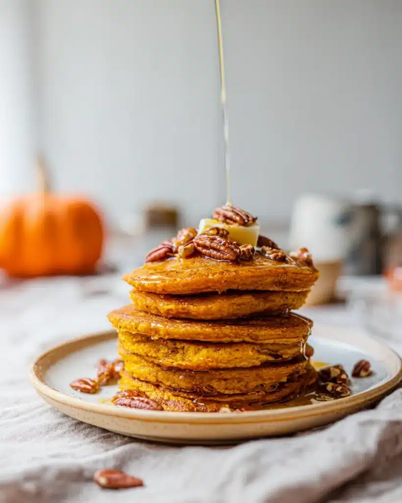 Healthy Pumpkin Pancakes 1 Fluffy pumpkin pancakes with maple syrup and pecans on a plate