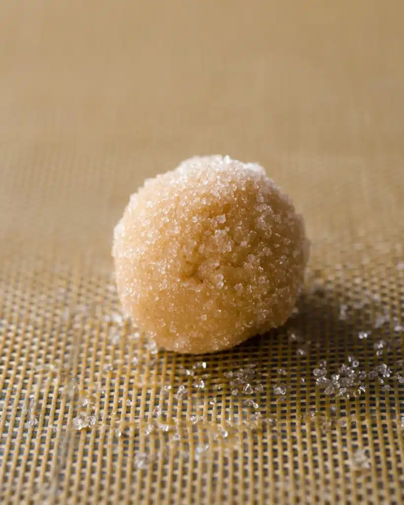 Sugar-coated peanut butter cookie dough ball on baking mat