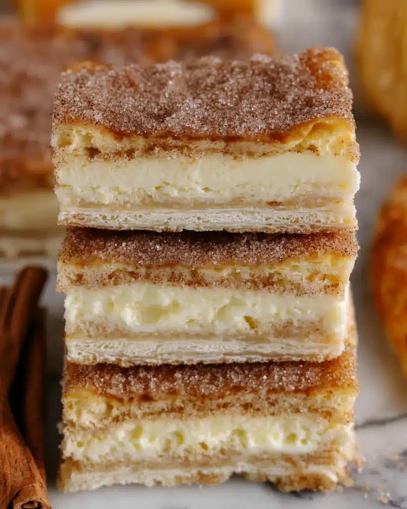 Simple Churro Cheesecake Recipe 1 Stacked churro cheesecake bars with flaky crust, creamy filling, and cinnamon sugar topping
