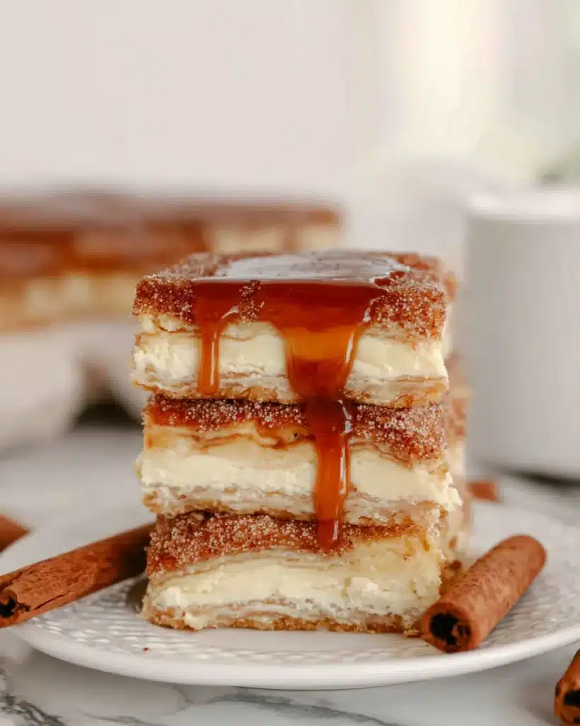 Simple Churro Cheesecake Recipe 4 Simple churro cheesecake bars drizzled with caramel sauce on a white plate