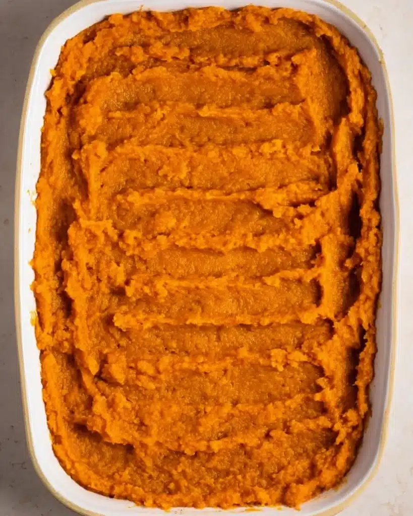 Sweet potato casserole base spread in a white baking dish