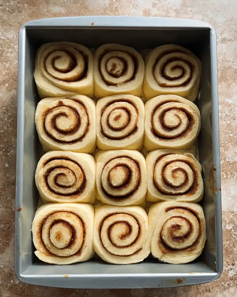 The Best Cinnamon Rolls EVER (Halloween Edition) 9 Unbaked cinnamon roll swirls arranged in a baking pan