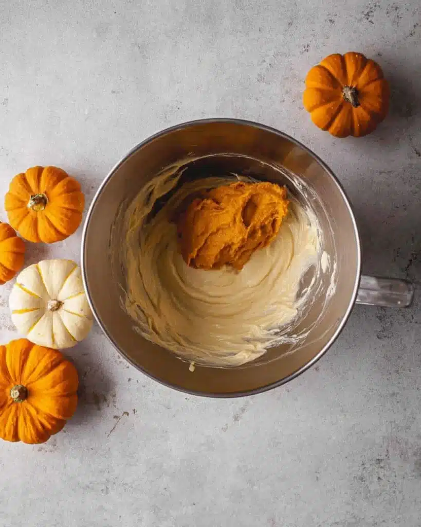 Pumpkin puree added to cheesecake batter in mixing bowl