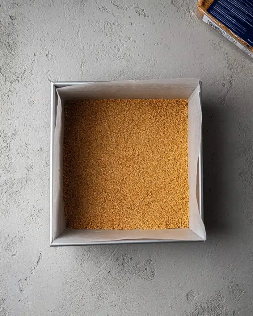Pressed graham cracker crust in baking pan for cheesecake bars