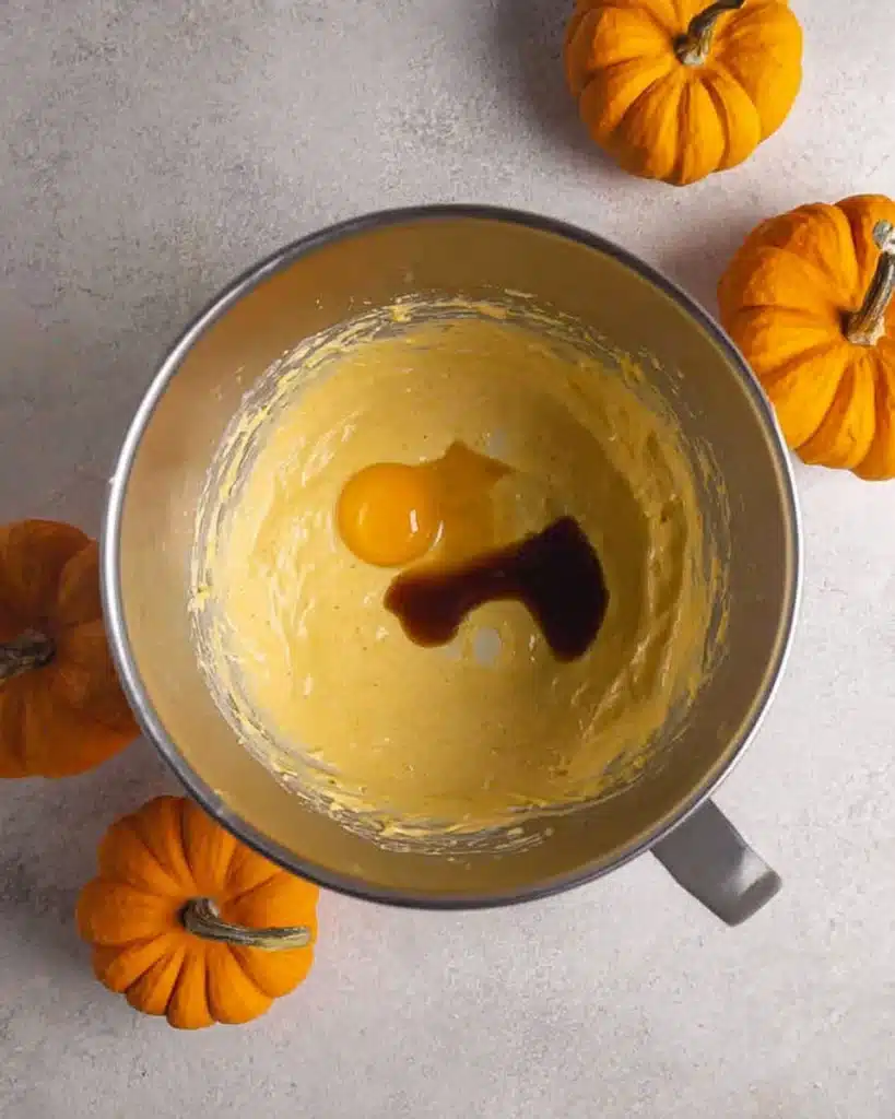 Egg and vanilla added to pumpkin cheesecake batter in bowl