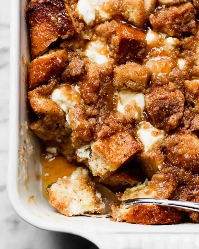 Baked Cream Cheese French Toast Casserole 8 Close-up of baked cream cheese French toast casserole in white dish with crumb topping
