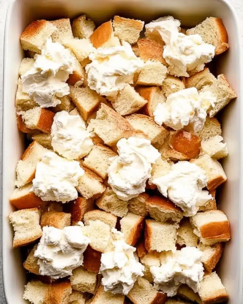 Baked Cream Cheese French Toast Casserole 4 Layered bread cubes and cream cheese in baking dish for French toast casserole