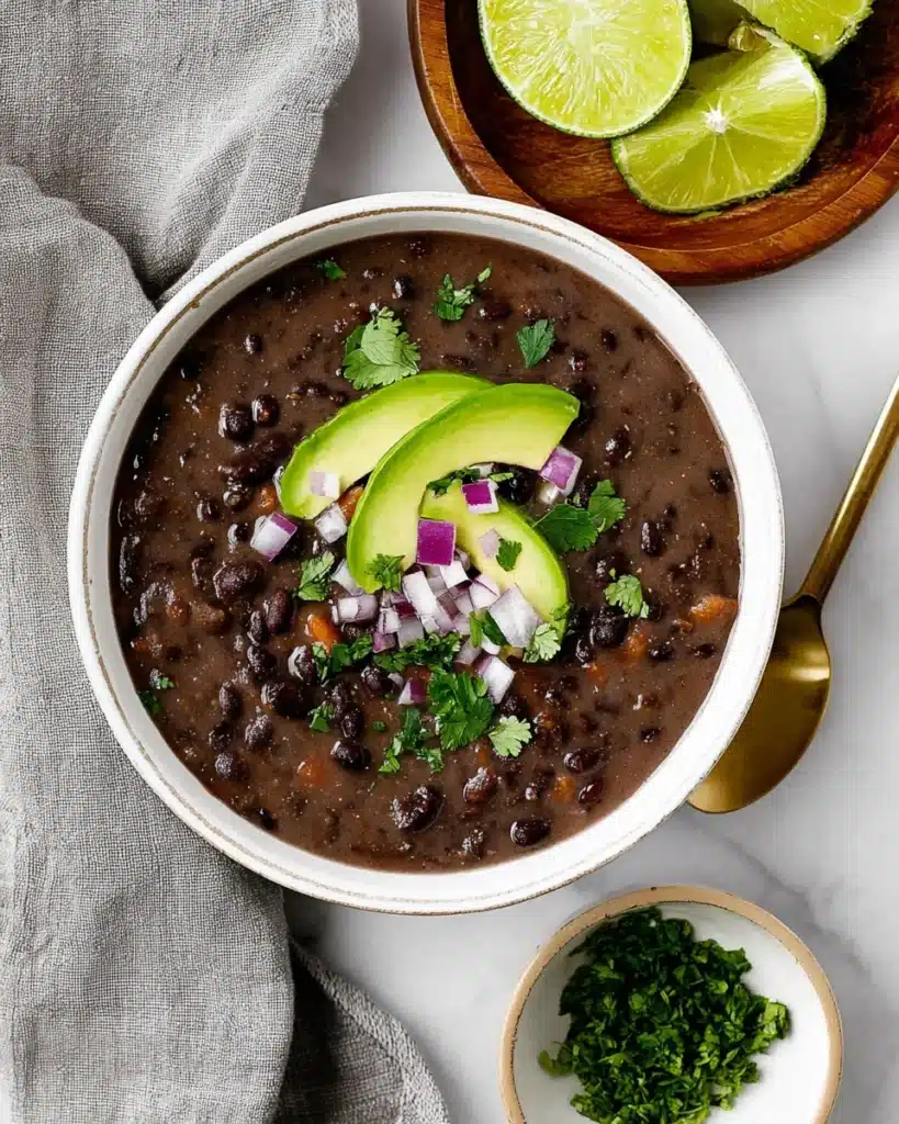Creamy black bean soup topped with avocado, red onion, and cilantro
