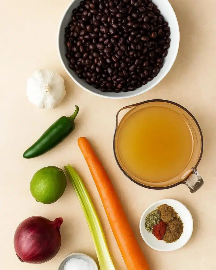 Flat lay of black bean soup ingredients on a beige stone background