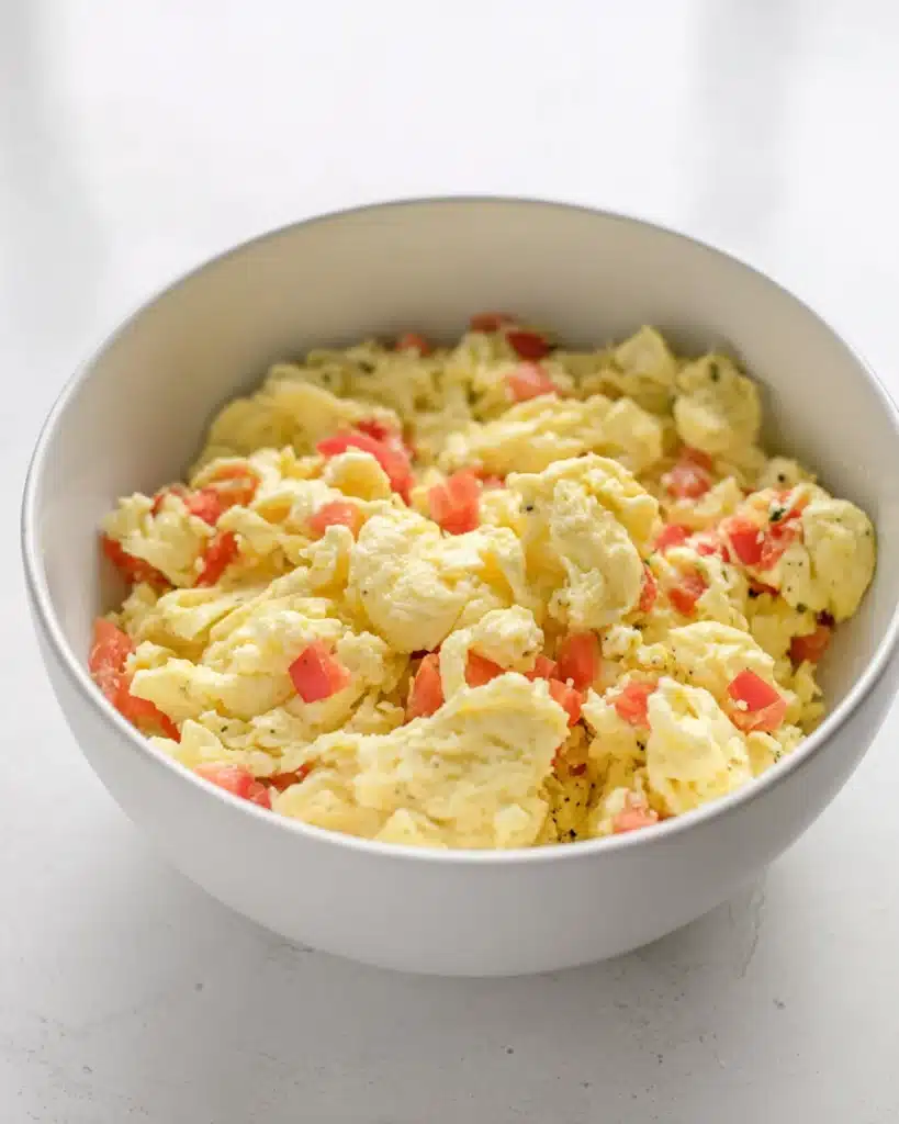 Bowl of scrambled eggs with diced red bell peppers