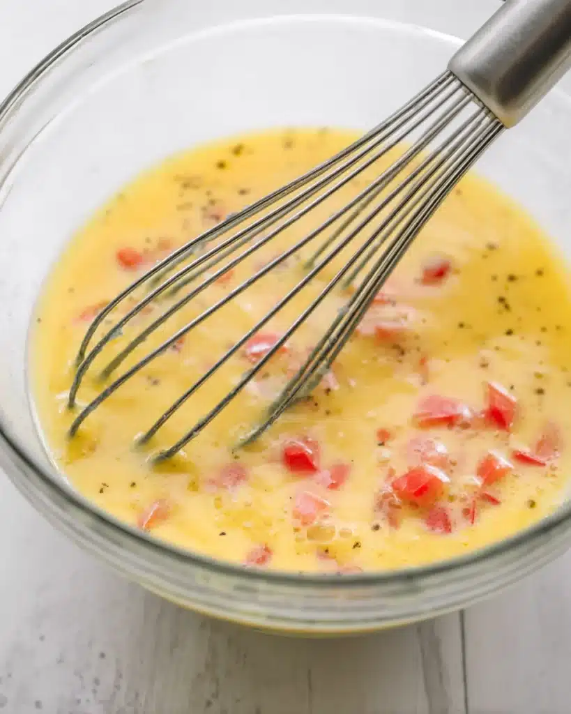 Whisked eggs with red bell peppers in a glass bowl