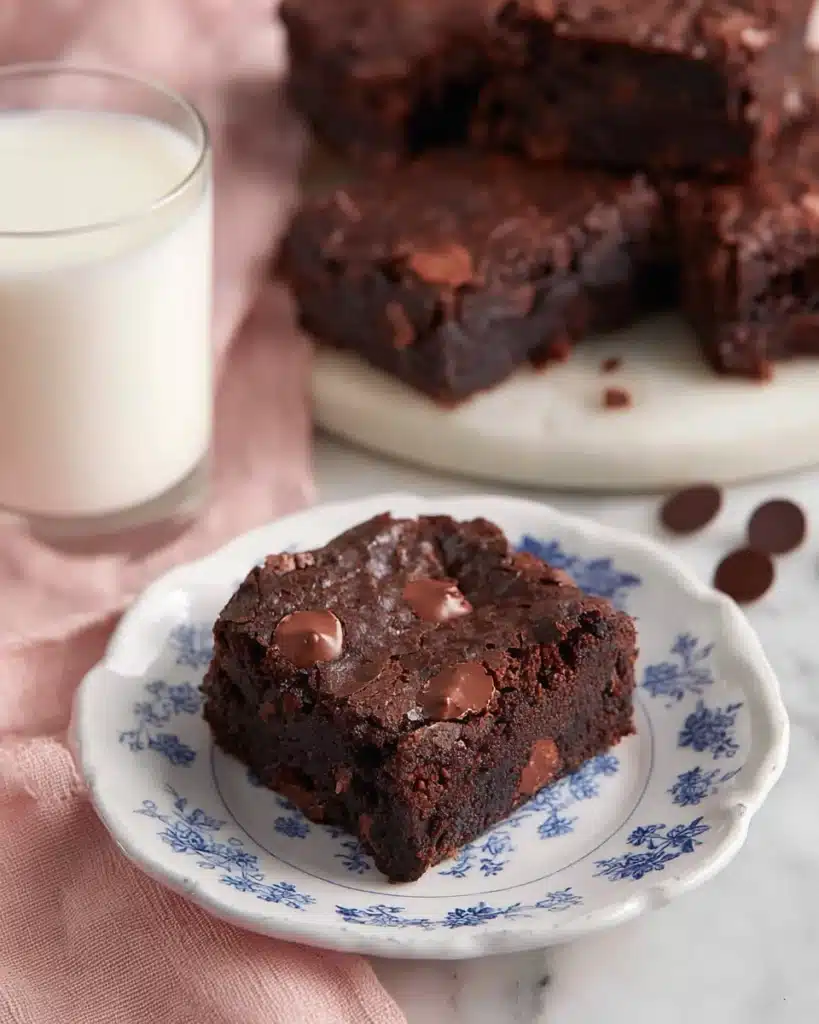 Fudgy chocolate brownie on blue floral plate with milk glass