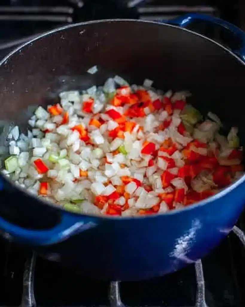 Cajun Potato Soup 3 Diced onions, red peppers, and celery cooking in a blue Dutch oven