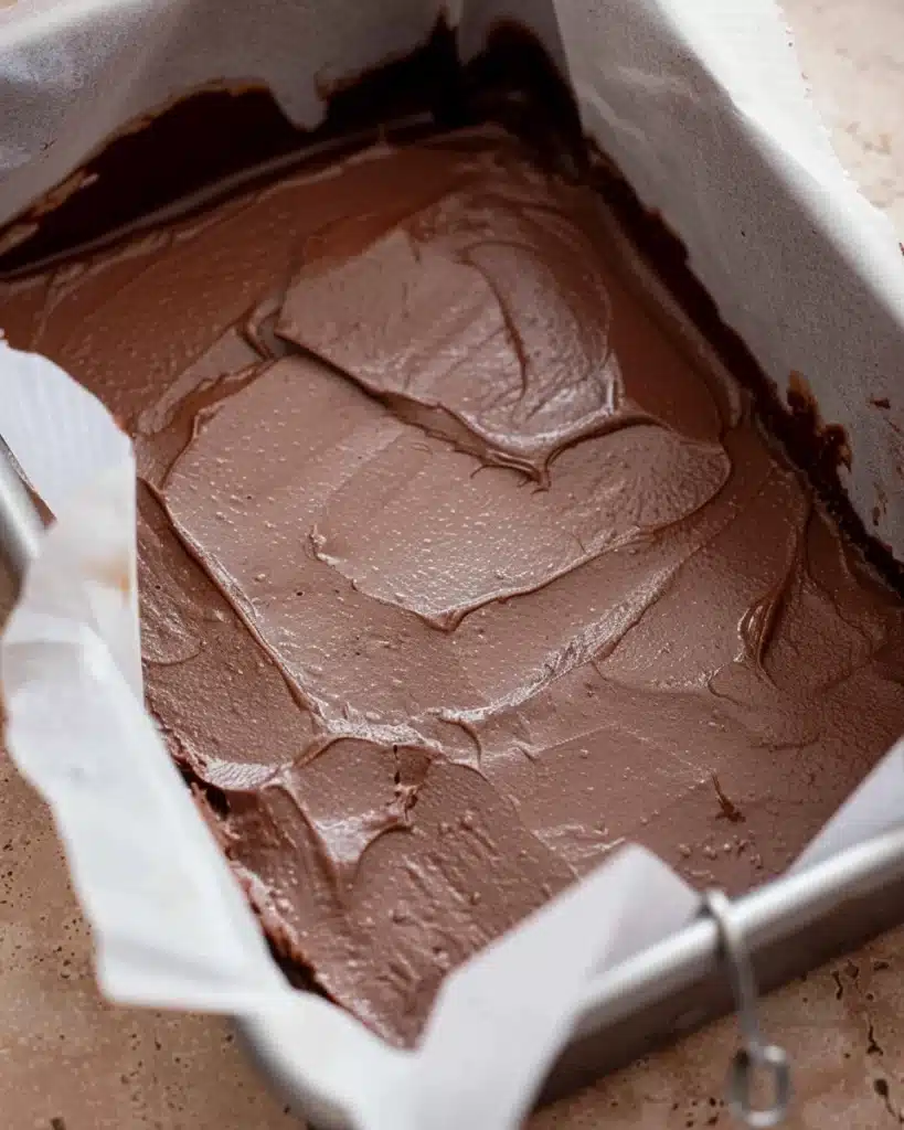 Chocolate fudge layer spread in a parchment-lined pan
