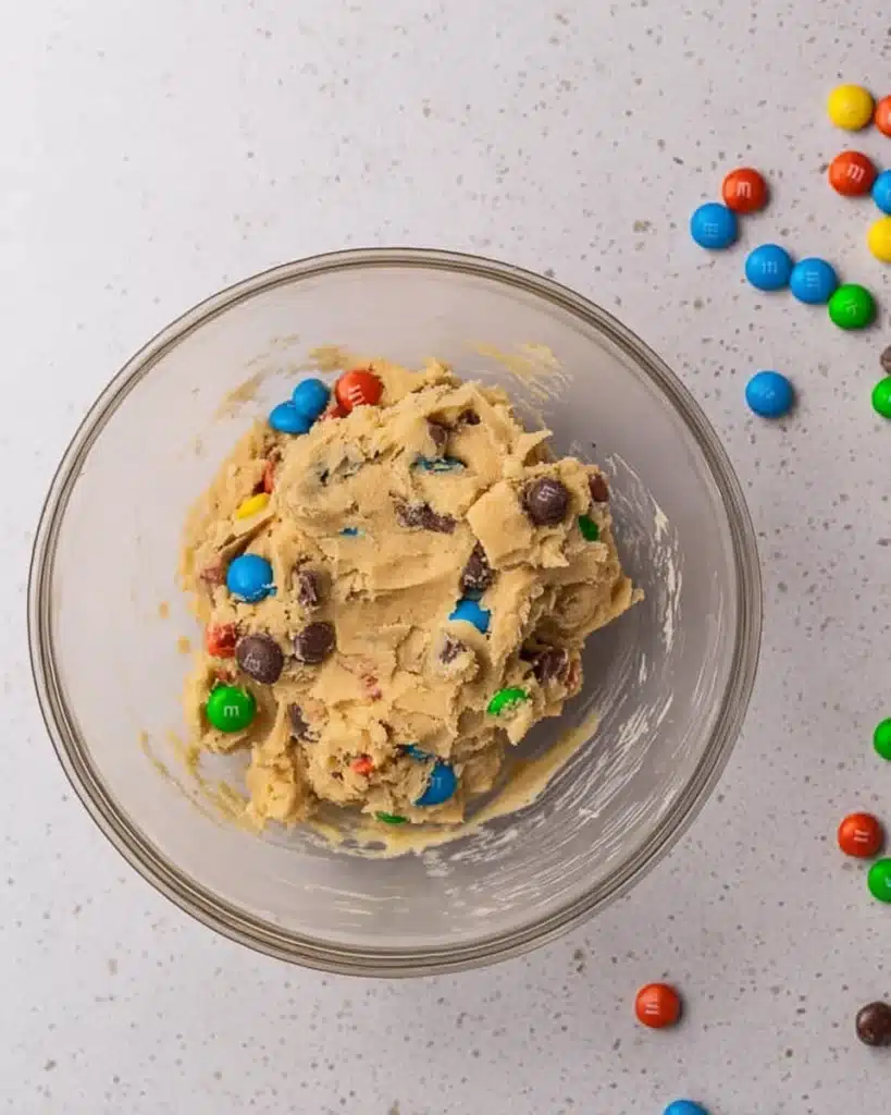 Crumbl Monster Cookie Recipe – Soft & Packed with M&M’s 3 Crumbl Monster cookie dough with M&M’s and chocolate chips in glass bowl