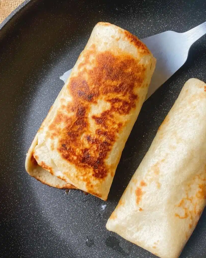 Toasting chicken wraps in pan until golden brown