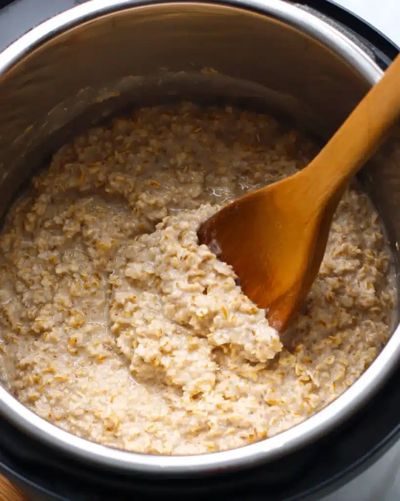 Creamy steel cut oats stirred with a wooden spoon in an Instant Pot