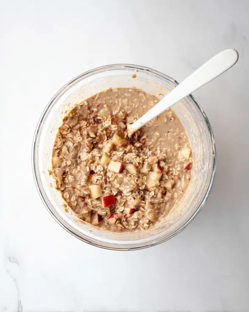 Oatmeal Apple Breakfast Bake Recipe 4 Oatmeal Apple Breakfast Bake batter with oats and apples in a glass bowl