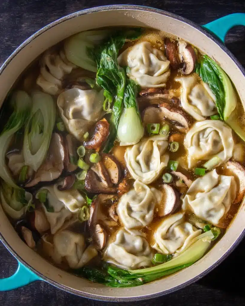 Simmering wonton soup with mushrooms and bok choy in broth