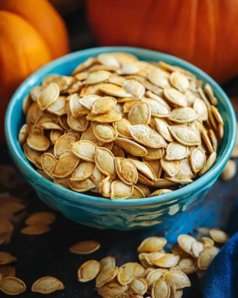 Roasted Pumpkin Seeds Recipe 1 Golden roasted pumpkin seeds in a blue bowl on autumn table