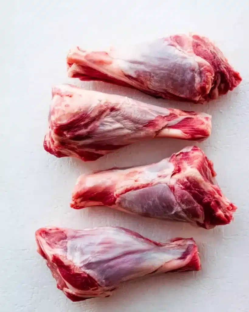 Slow Cooked Lamb Shanks in Red Wine Sauce 2 Raw lamb shanks on a white surface ready for slow cooking