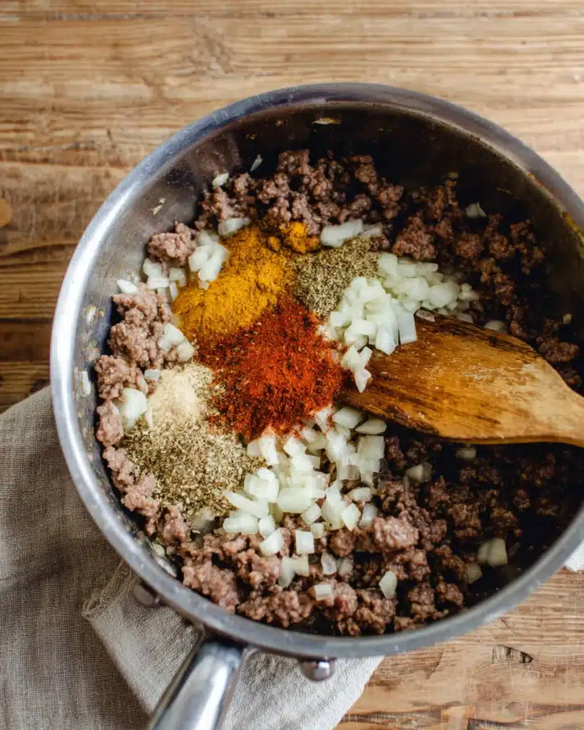 Adding spices and garlic to ground beef for slow cooker chili