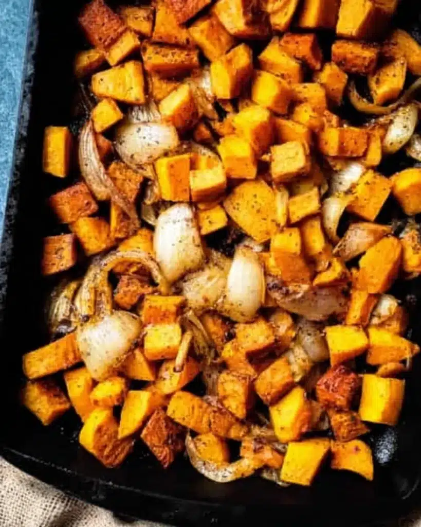 Chopped butternut squash, sweet potatoes, and onions on a tray for roasting