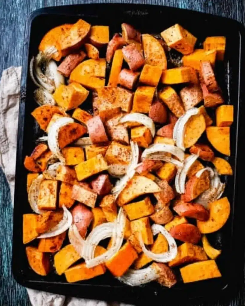 Chopped butternut squash, sweet potatoes, and onions on a tray for roasting