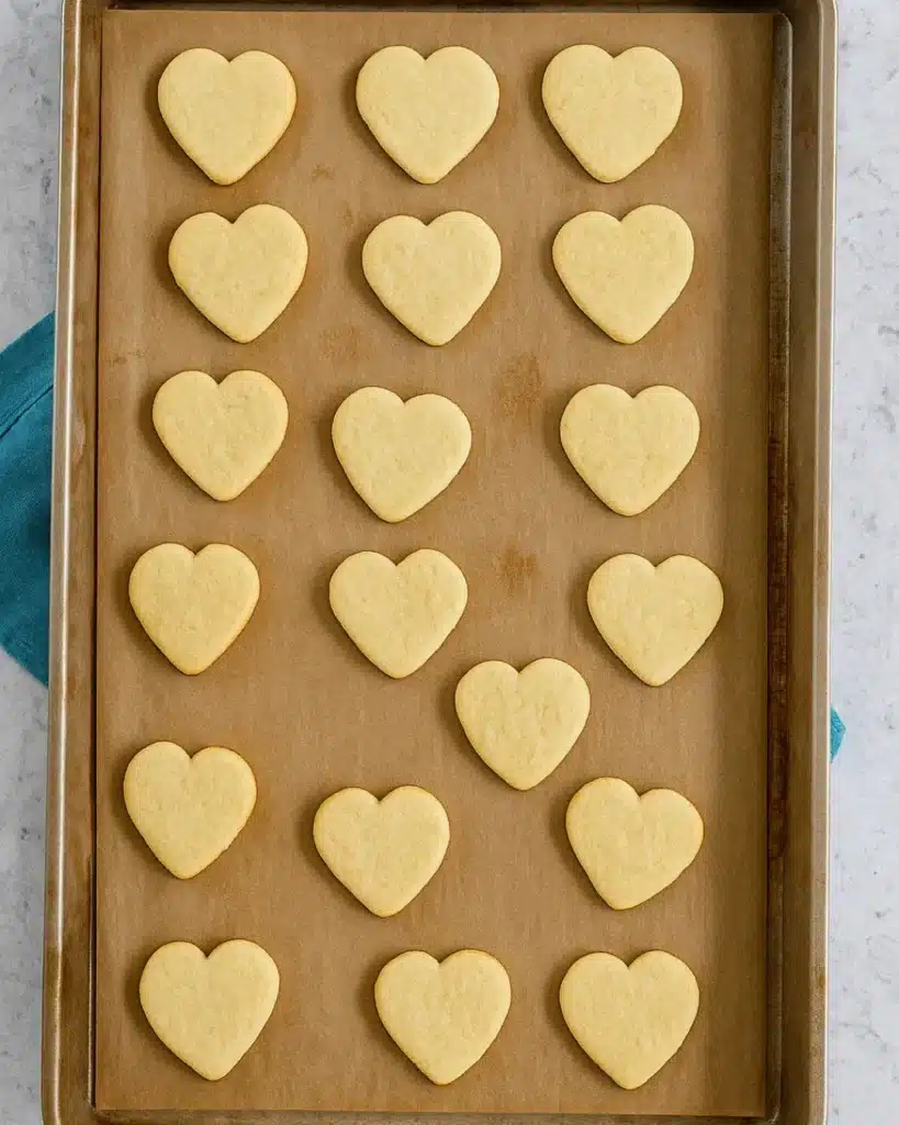 Heart-shaped shortbread cookies on parchment-lined baking sheet