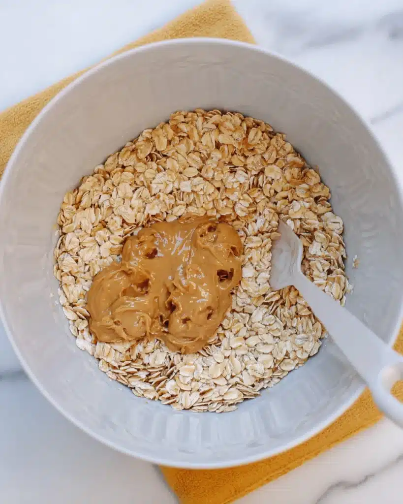 Oats and peanut butter in mixing bowl for chocolate no bake cookies