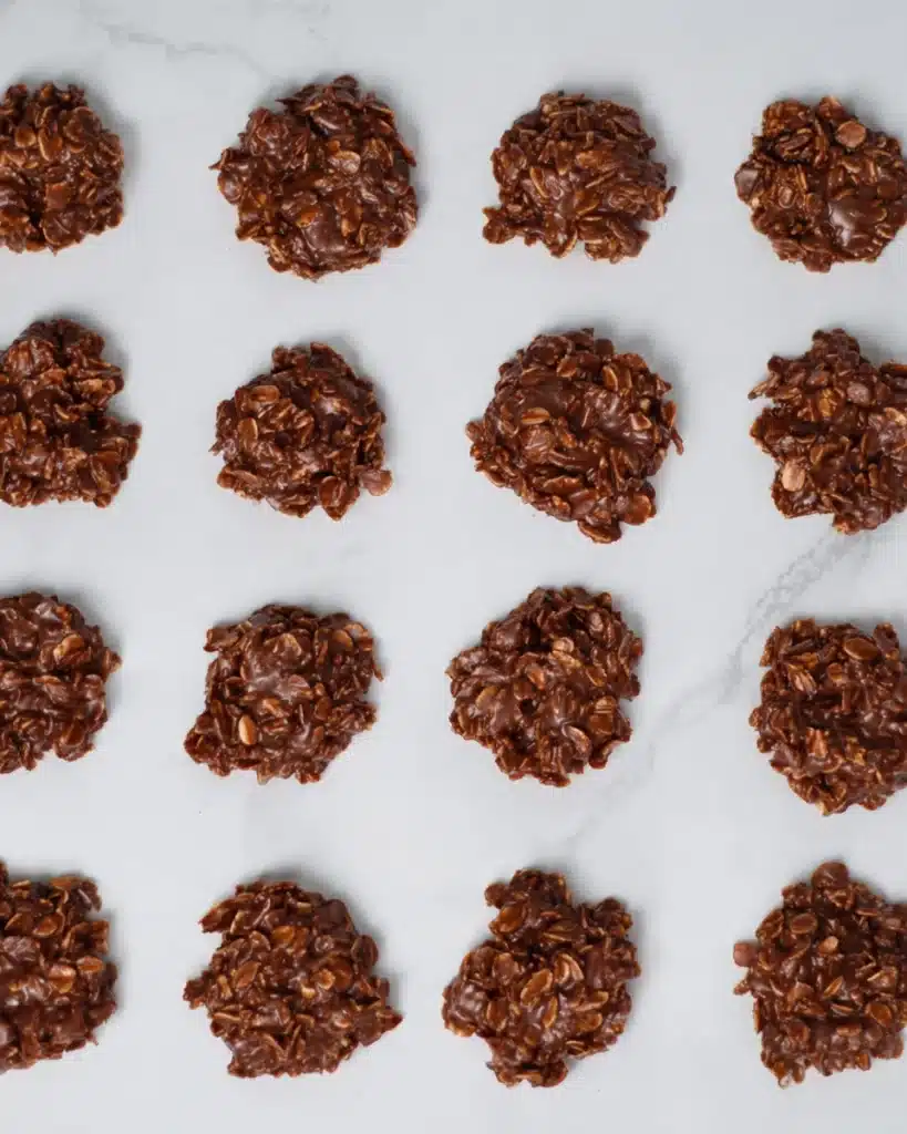 Rows of chocolate no bake cookies cooling on white parchment paper