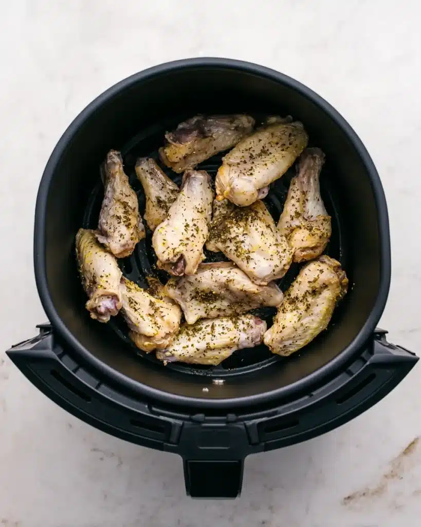Raw lemon pepper chicken wings in air fryer basket ready to cook