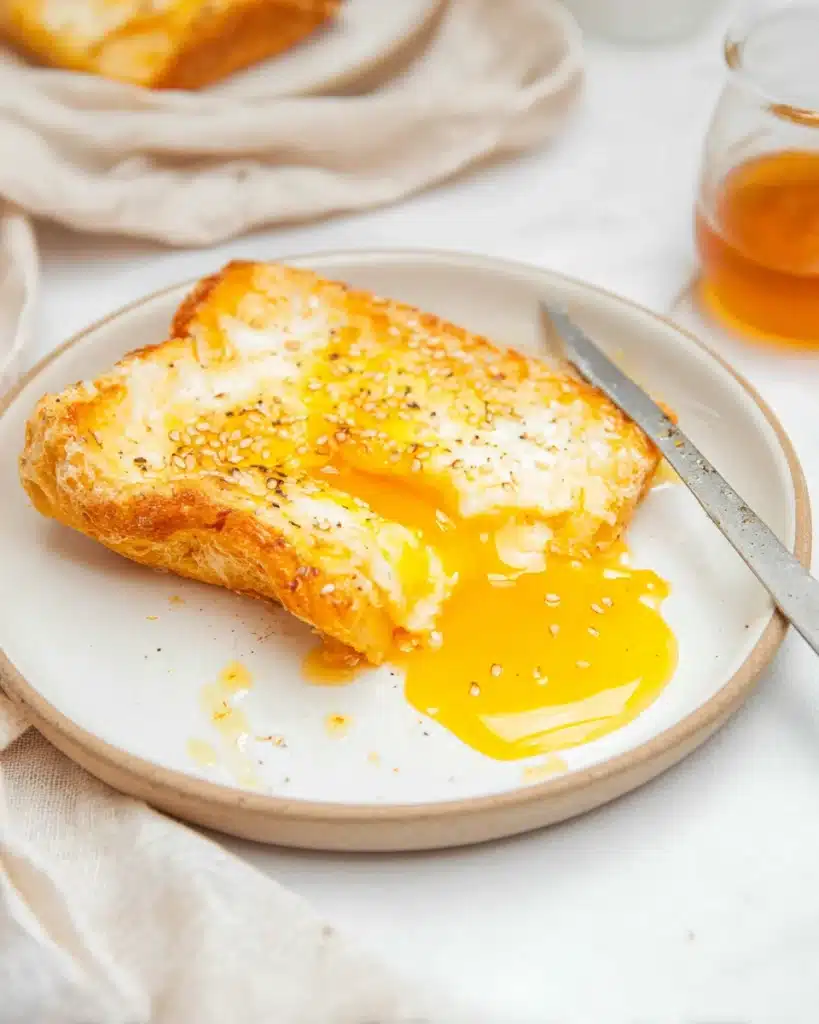 Air fryer egg and cheese toast with melted mozzarella and runny yolk on a white plate