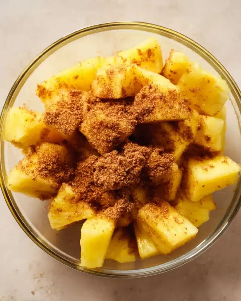 AIR FRYER PINEAPPLE (CARAMELIZED AND SWEET IN MINUTES) 2 Fresh pineapple tossed with brown sugar and cinnamon in a glass bowl