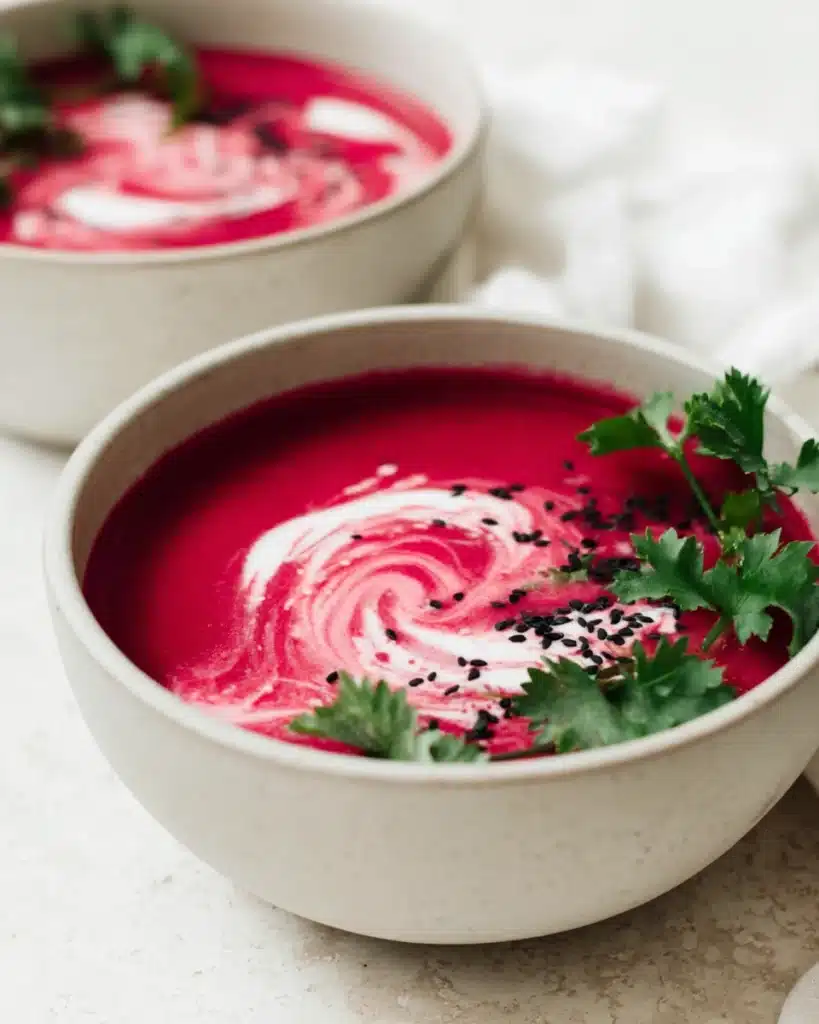 Beet Soup (Smooth and Velvety) 1 Smooth beet soup with coconut cream swirl and parsley garnish in white bowl