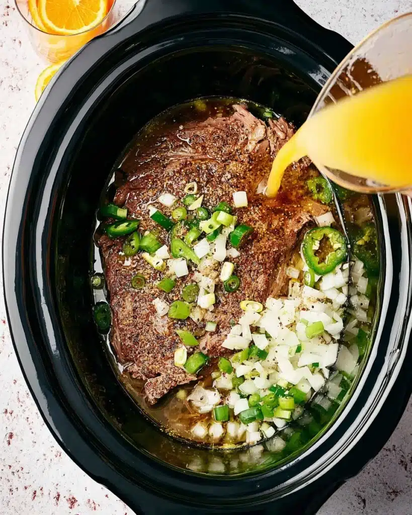 Slow Cooker Carnitas Tacos (Juicy, Crispy, and Easy) 2 Pork shoulder with onions and jalapeños in slow cooker for carnitas tacos