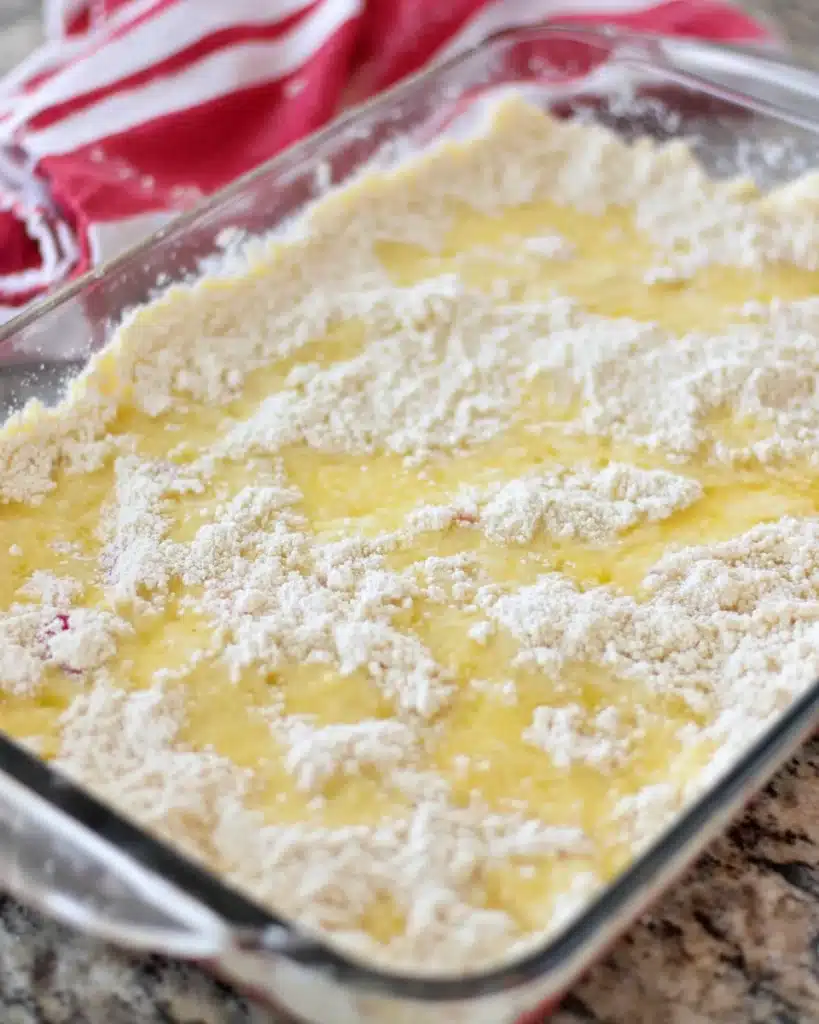 Cherry Dump Cake 3 Unbaked cherry dump cake with butter and cake mix in glass dish