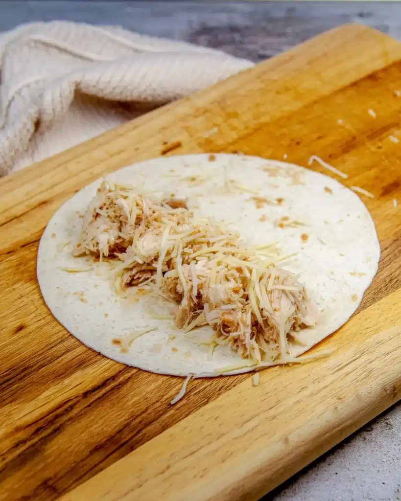 Flour tortilla filled with shredded chicken and cheese for creamy white chicken enchiladas