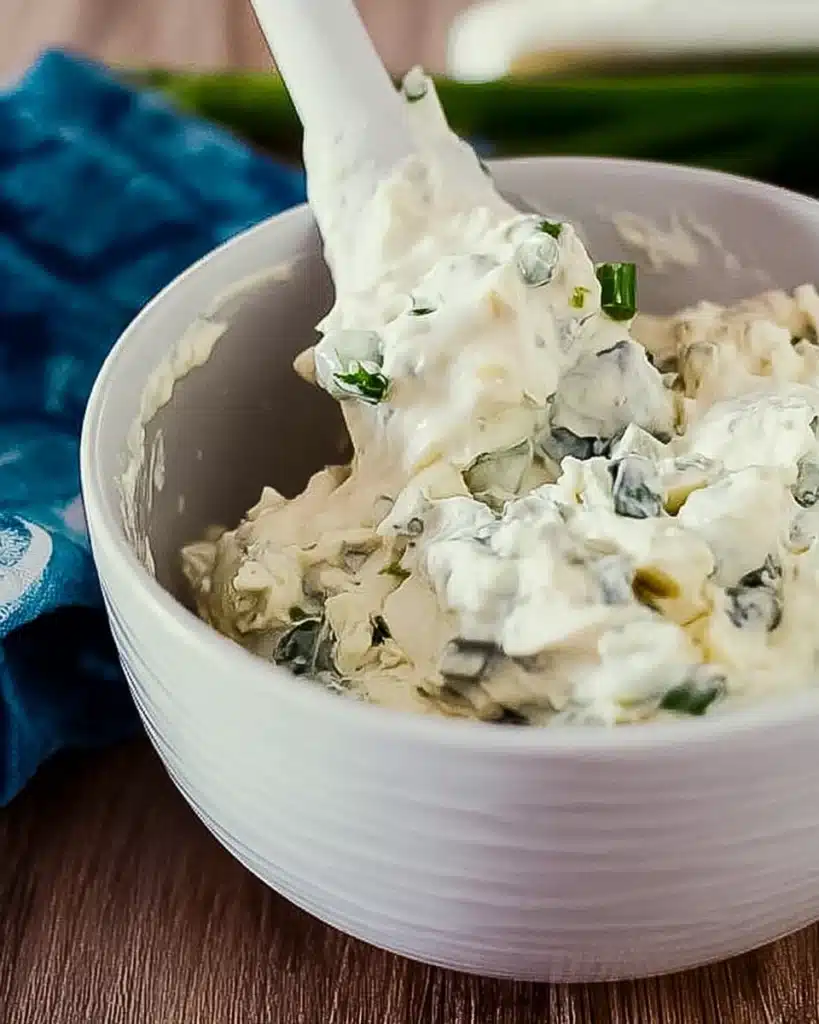 Crispy Baked Buffalo Wings – The Ultimate Game Day Appetizer 5 mixing creamy blue cheese dip with scallions in a white bowl
