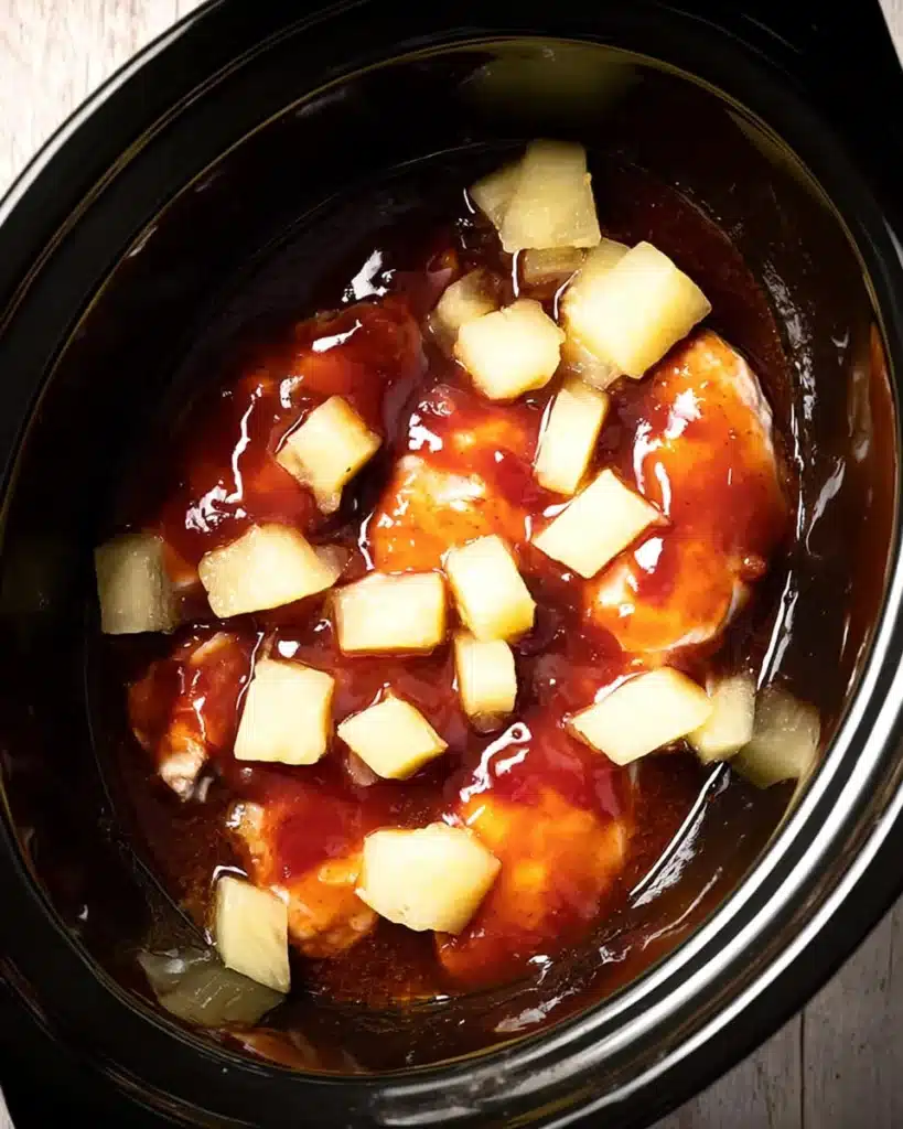 Crockpot Hawaiian BBQ Chicken (Slow Cooker Recipe) 2 Raw chicken with BBQ sauce and pineapple in a slow cooker