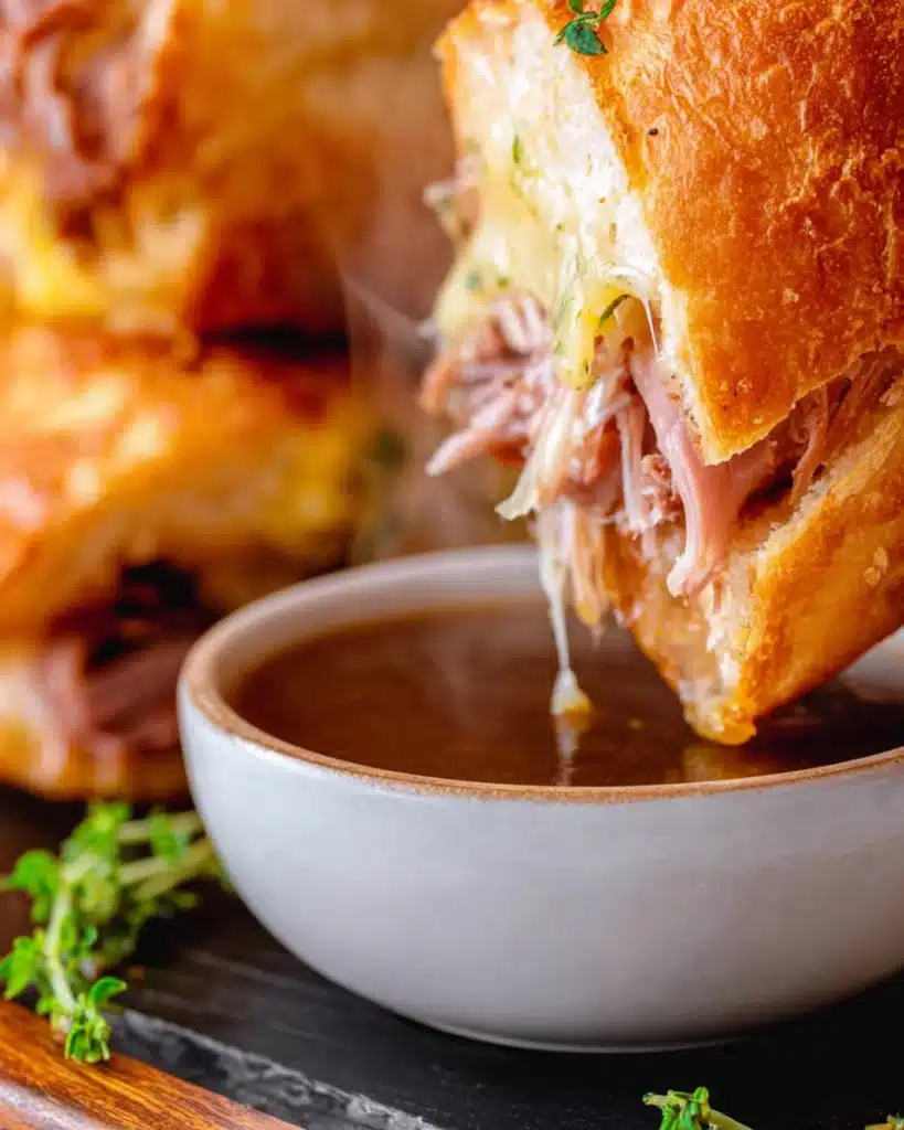 French Dip Sliders 5 French Dip Slider dipped into au jus sauce with melted cheese and roast beef