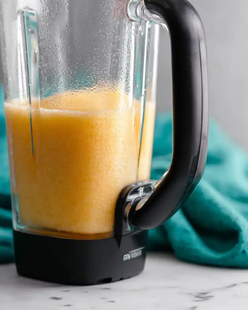Frozen Peach Bellini 3 Blending frozen peach Bellini mixture in a blender with teal fabric on marble